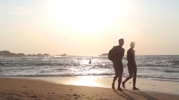 Coppia turistica in silhouette passeggiando sulla spiaggia al tramonto . — Video Stock