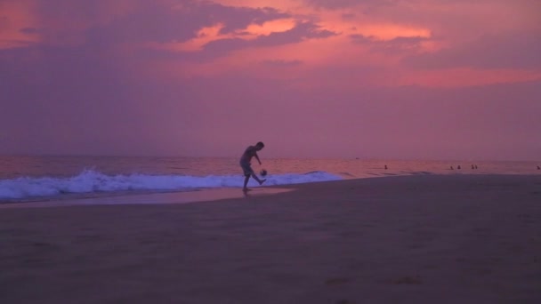 Gente practicando deportes en la playa de arena al atardecer . — Vídeos de Stock