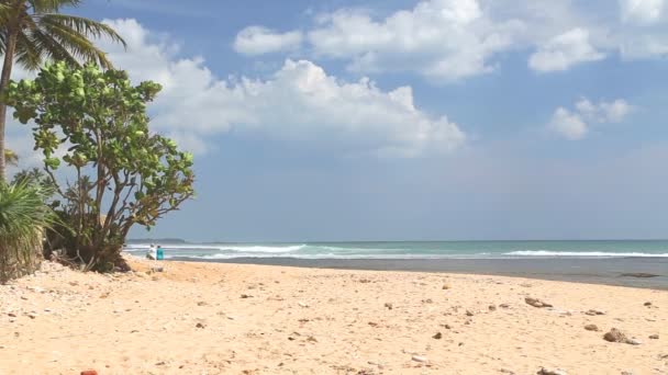 Vista mar em Hikkaduwa com ondas salpicando a praia enquanto as pessoas estão passando — Vídeo de Stock