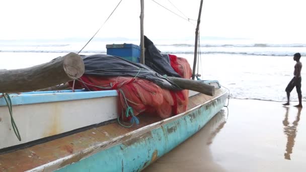 Boot am Strand in Weligama mit vorbeifahrenden Surfern — Stockvideo