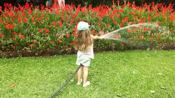 Niña regando flores en el jardín botánico — Vídeo de stock