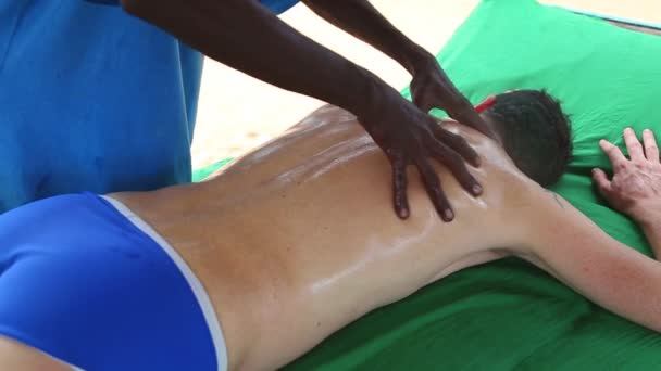 Sri Lankan man giving oil massage to Caucasian man — Stock Video