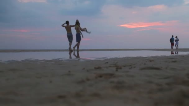 Familie wandelen op het strand en kind in de lucht gooien — Stockvideo