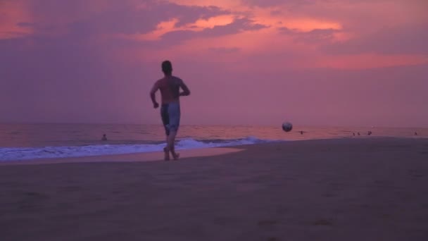 Gente practicando deportes en la playa de arena al atardecer . — Vídeo de stock