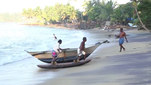 Fishermen pulling boat out of the ocean — Stock Video