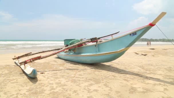 Traditional wooden fishing boat on beach in Weligama with people passing by — Stock Video