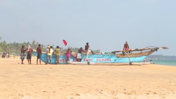 Weergave van de lokale bevolking permanent en zittend op de boot op Hikkaduwa strand — Stockvideo