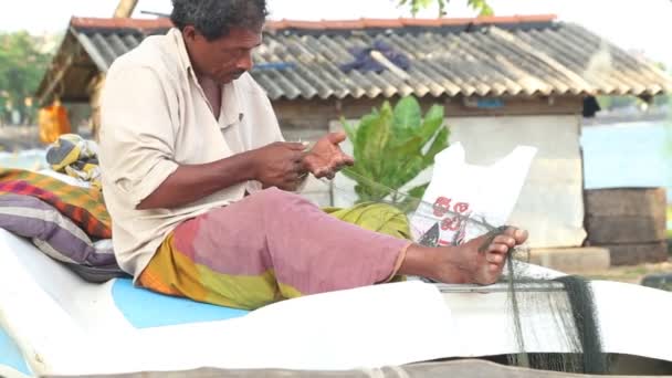 Fisherman sitting on boat and fixing fishing nets — Stock Video