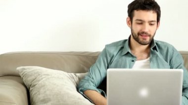 Oturma odasında dizüstü bilgisayar kullanan adam.