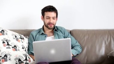 Oturma odasında dizüstü bilgisayar kullanan adam.