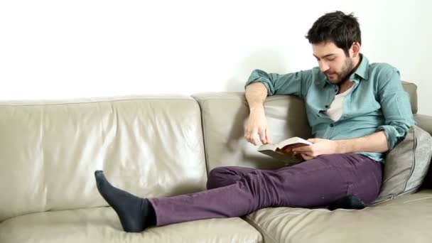 Man reading book in living room — Stock Video