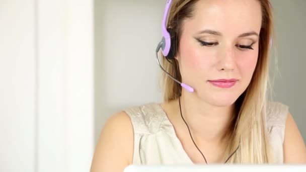 Woman with headphones on computer talking to customer — Stock Video