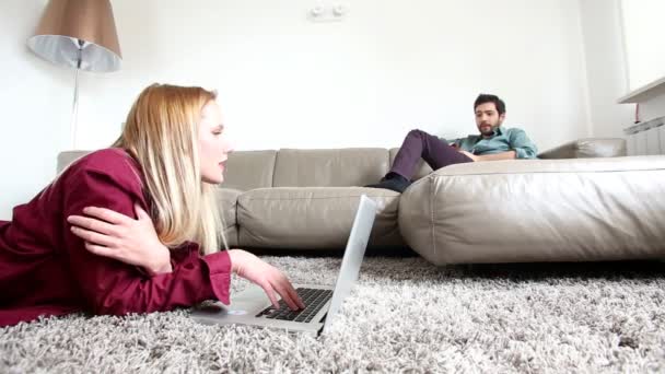 Γυναίκα που ψάχνει στο lap-top με άτομο στον καναπέ — Αρχείο Βίντεο