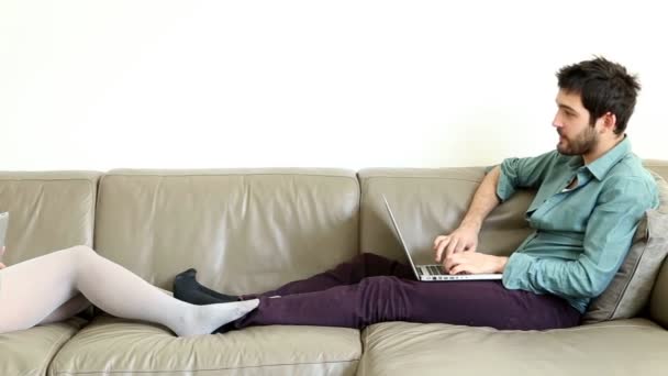 Pareja hablando y usando computadoras en el sofá — Vídeos de Stock