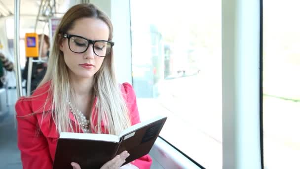 Nő ül, és az olvasás a villamoson — Stock videók