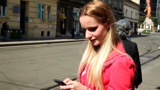 Дівчина в червоному пальто друкує по телефону — стокове відео