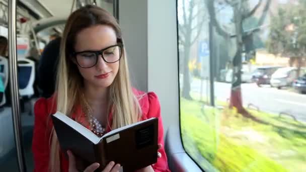 Frau sitzt und liest in der Straßenbahn — Stockvideo