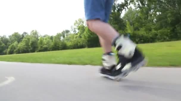 Молодий красивий чоловік катається на роликах в парку — стокове відео