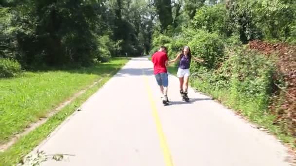 Жінка і чоловік катаються на роликах в сонячний день в парку — стокове відео