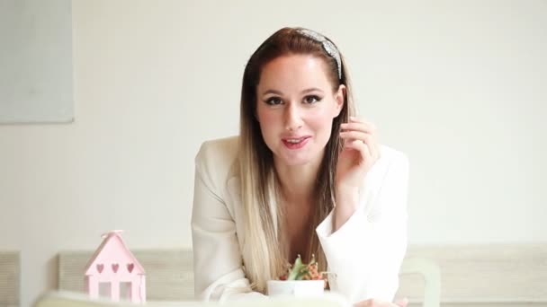 Hermosa joven sentada en el café y sonriendo — Vídeos de Stock