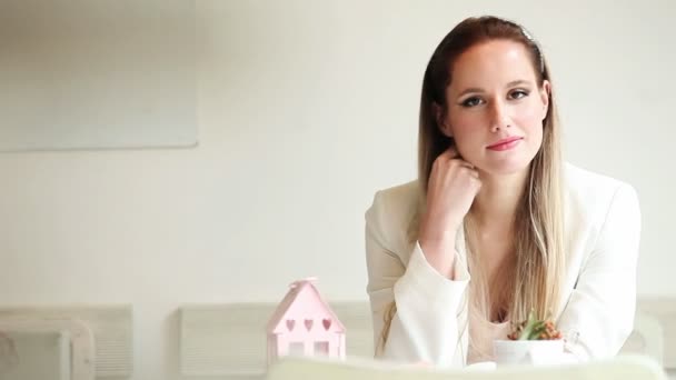 Mooie jonge vrouw zitten in het cafe en glimlachen — Stockvideo