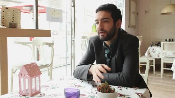 Csinos fiatal ember beszél egy kávézóban — Stock videók
