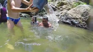 Adam nehre oturan diğer adam üzerinde su dökülen