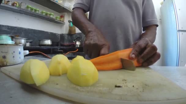 Seorang pria mengiris wortel dan kentang dengan pisau di dapur . — Stok Video
