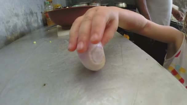Ξανθό κορίτσι παίζει με κρεμμύδι στην κουζίνα — Αρχείο Βίντεο