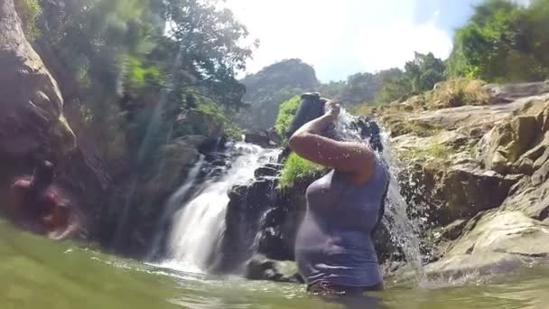 Frau steht im Fluss und schüttet Wasser aus Eimer — Stockvideo