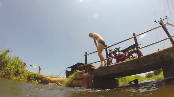 Jeune fille sautant du pont dans la rivière . — Video