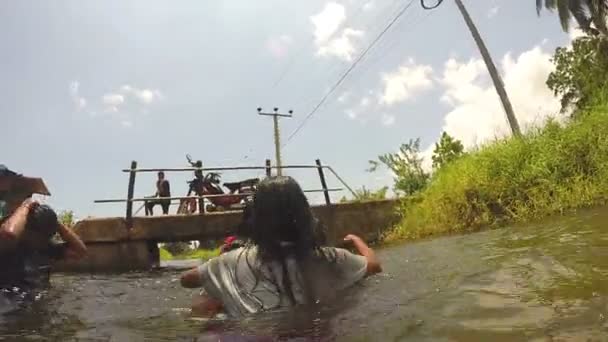 Chicas jóvenes jugando y divirtiéndose trepándose en el río . — Vídeos de Stock