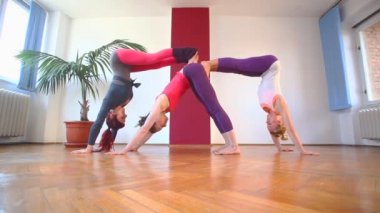 Üç kadın akrobatik yoga yaparken