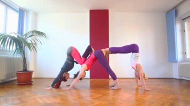 Üç kadın akrobatik yoga yaparken