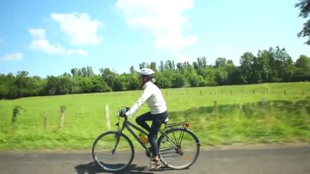 Γυναίκα ποδηλασία στο δρόμο στην ύπαιθρο — Αρχείο Βίντεο