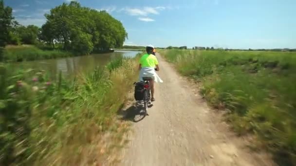 Сімейна пара катається на велосипеді біля річки — стокове відео