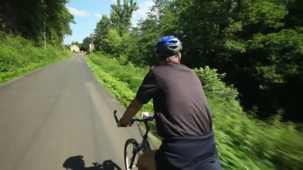 Чоловік їде на велосипеді по дорозі в сільській місцевості — стокове відео