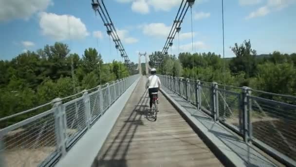 Kvinna cyklar på vägen över bron — Stockvideo