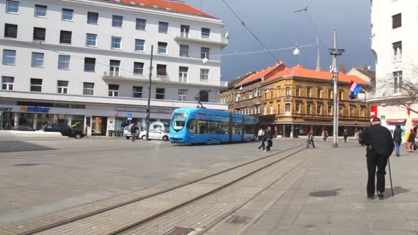 Les gens marchent le long de la rue de la ville avec de vieilles maisons et voyagent en tramway à Zagreb — Video