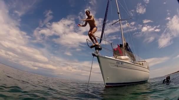 Человек, прыгающий в море с лодки — стоковое видео