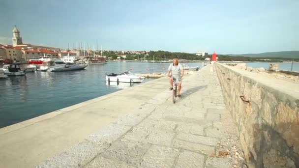 Man cycling in harbour of old town Krk — Stock Video