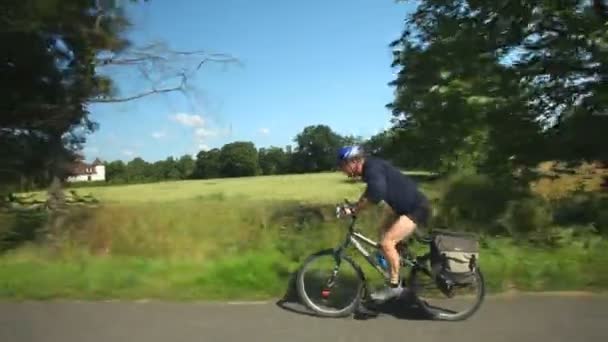Чоловік їде на велосипеді по дорозі — стокове відео