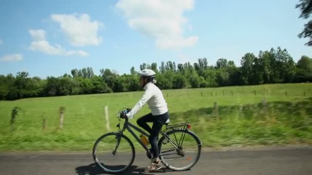 Kvinnan cykling på väg på landsbygden — Stockvideo