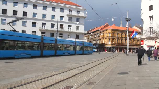 La gente camina por la calle de la ciudad con casas antiguas y viaja en tranvía en Zagreb — Vídeos de Stock