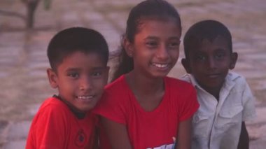 Sahilde oturan üç yerel çocuk