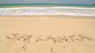 Kelime Sri Lanka kum plaj üzerine yazılmış yaklaşan dalga okyanus
