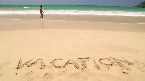 Les gens marchant devant le mot vacances écrit dans le sable — Video