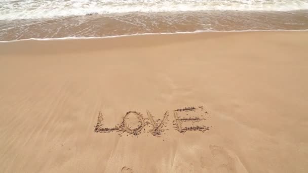 Océano ola cubriendo palabra amor escrito en arena en la playa — Vídeos de Stock