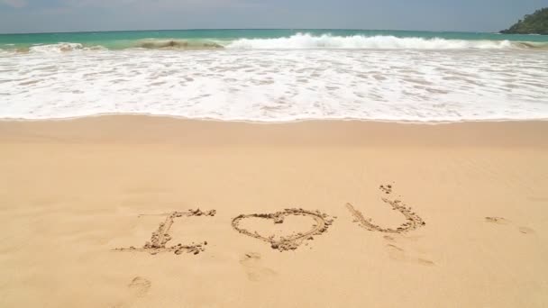 Océano ola cubriendo palabras Te amo escrito en arena en la playa — Vídeo de stock