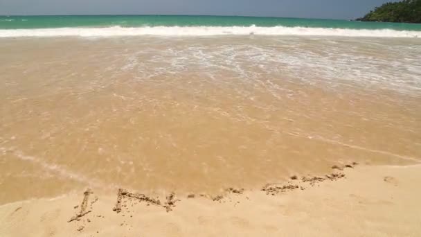 Vlny oceánu pokrývá cestování slovo napsané v písku na pláži — Stock video